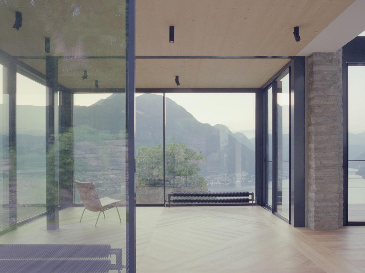 Living room in the glass pavilion with mountain and lake view